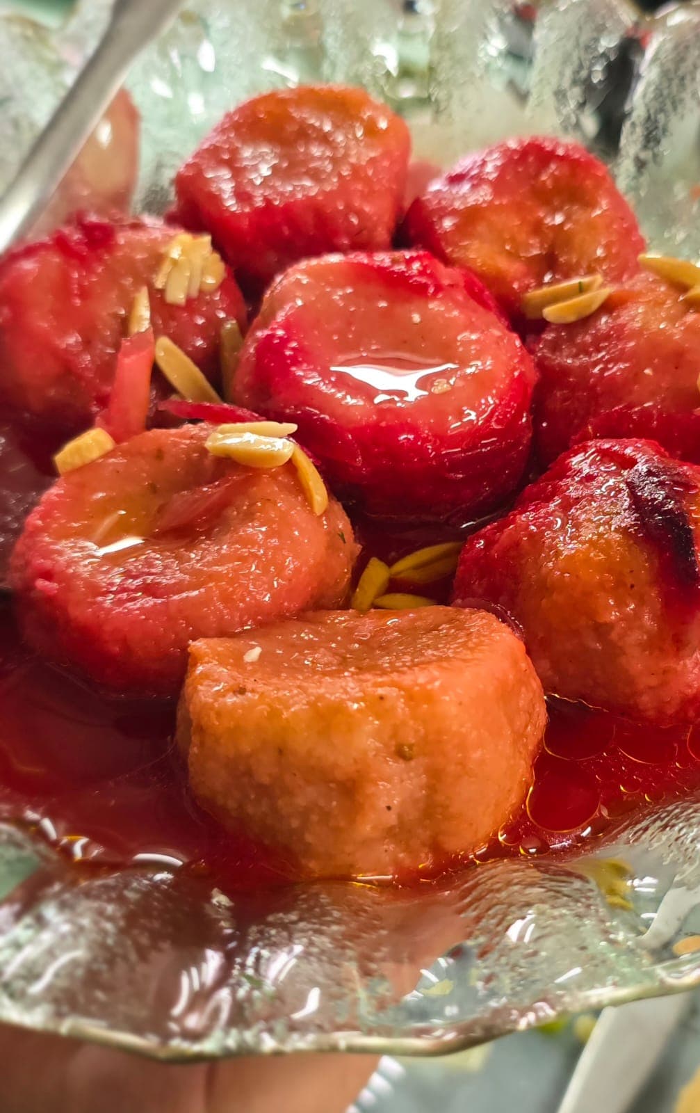 Kubbeh in beet — Persian beet-stained kubbeh dumplings garnished with slivered almonds, on a glass plate