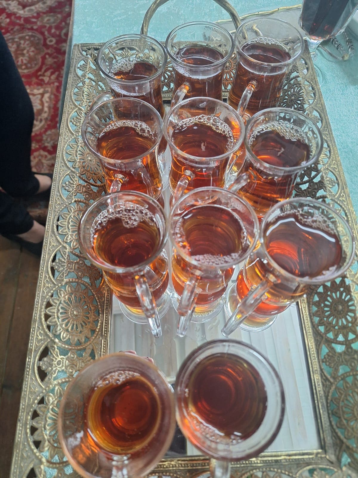 Persian tea — an ornate brass tray set with glass estekan cups filled with deep amber tea