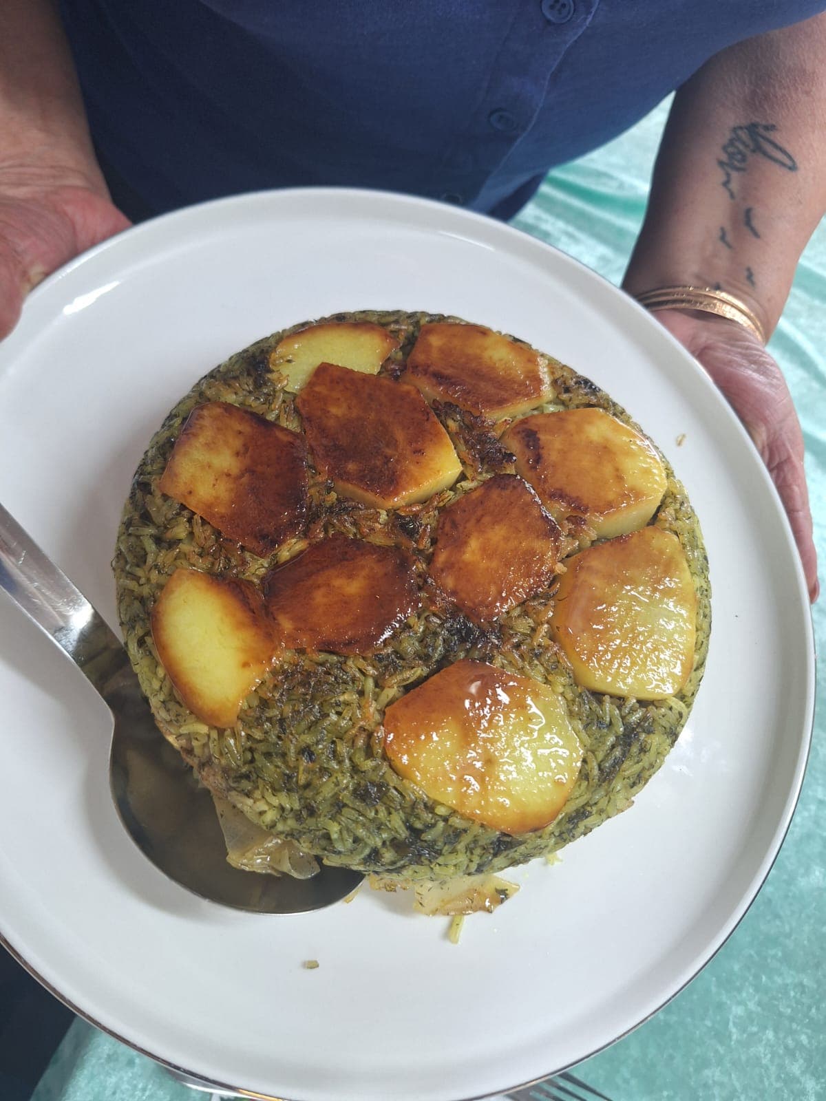 Persian polo rice crowned with a golden potato tahdig, plated on a vintage rose-pattern dish