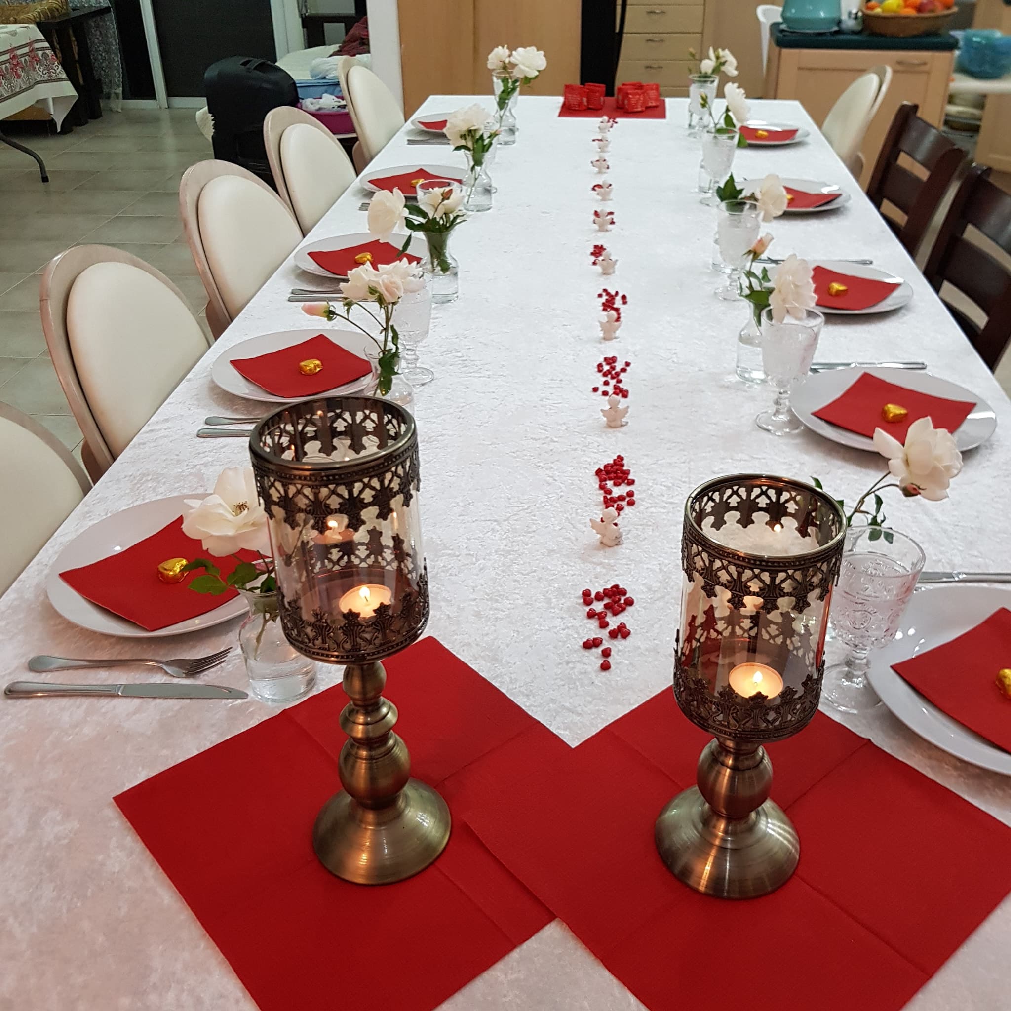 Pergola table set for guests with red linen napkins, white flowers and carved copper lanterns