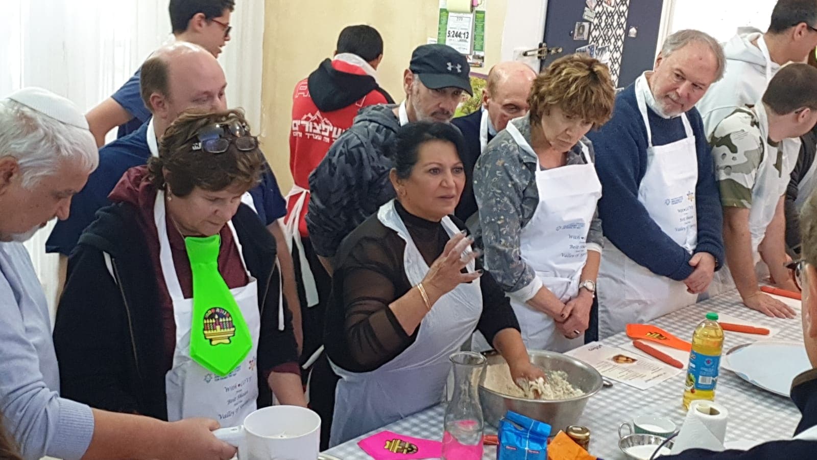 A group of guests at a cooking workshop with Lili Twizer, all in aprons kneading dough